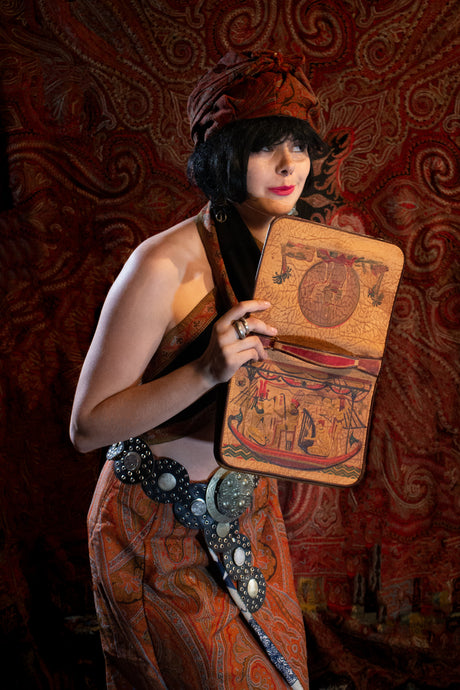 Model peeks into vintage embossed leather Egyptian handbag.