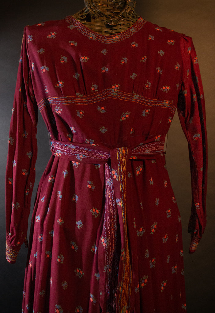 Closeup of 1970's Afghan maxi dress showing multicolored stitching on bodice, neck and cuffs, and matching belt.