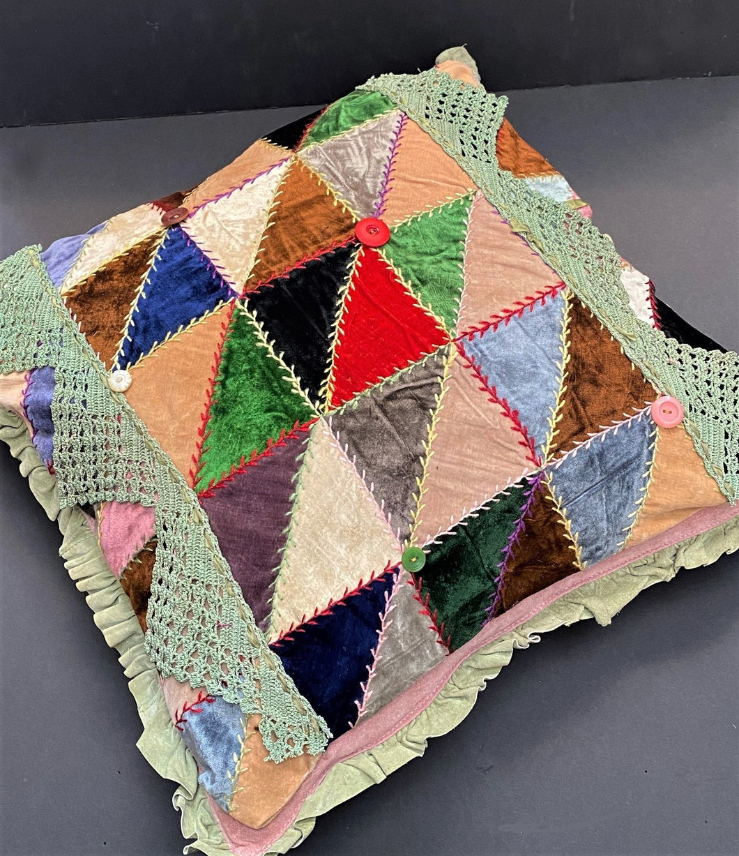 Upcycled harlequin patchwork pillow adorned with crochet, leather, lace, and buttons