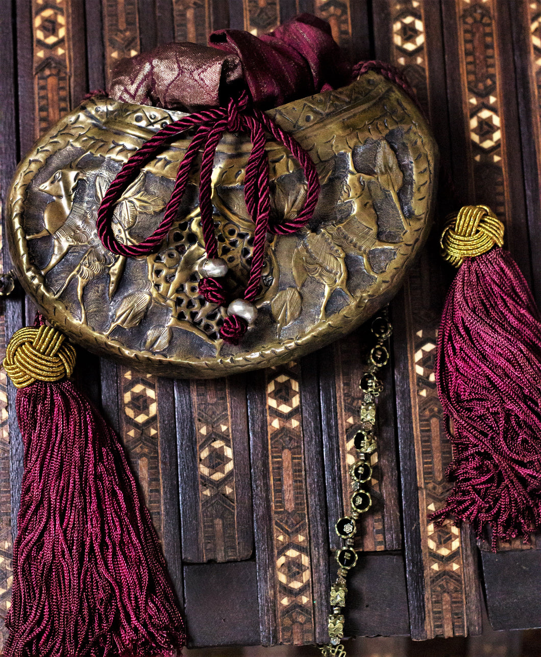 Brass Sufi kashkul reimagined as an evening bag, with silk sari lining, tassels; drawstring closure; beaded strap.